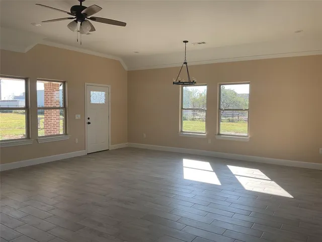 an empty room with wooden floor chandelier and windows