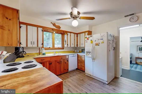 a large kitchen with stainless steel appliances a stove a refrigerator a sink a dining table and chairs with wooden floor