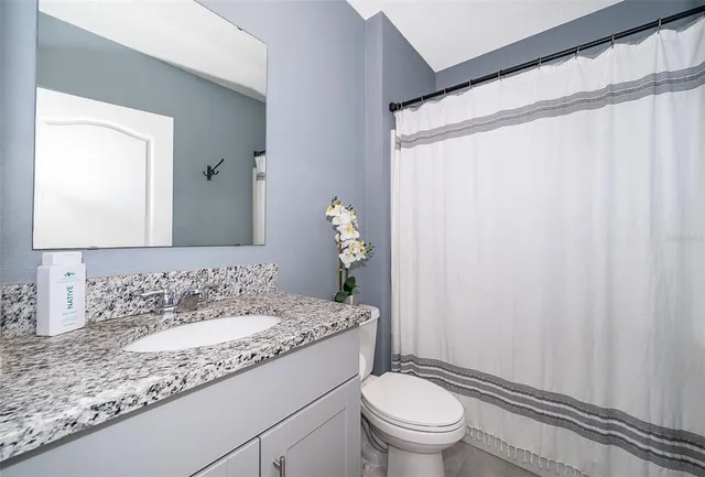 a bathroom with a granite countertop sink toilet and a mirror