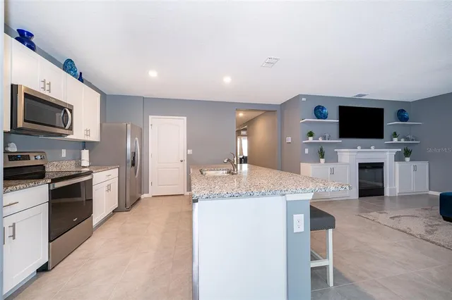 a large kitchen with granite countertop a stove top oven a sink dishwasher a dining table and chairs with wooden floor