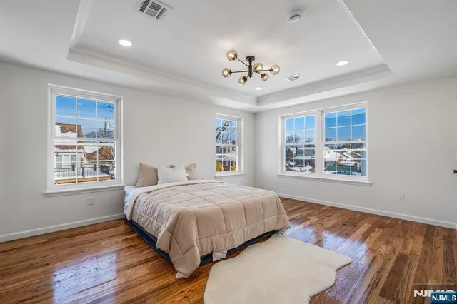 a bedroom with a large bed chandelier and a window