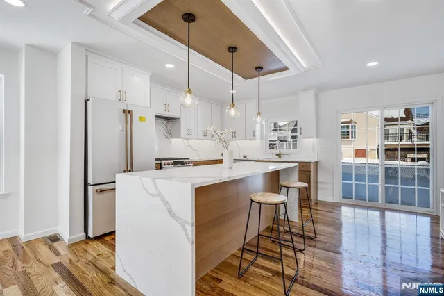 a kitchen with kitchen island a stove a refrigerator a sink and a dining table with wooden floor