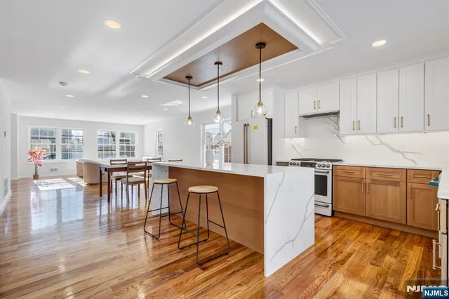 a kitchen with stainless steel appliances granite countertop a stove top oven a sink a dining table and chairs with wooden floor