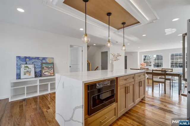 a kitchen with stainless steel appliances granite countertop a stove top oven a sink a dining table and chairs with wooden floor