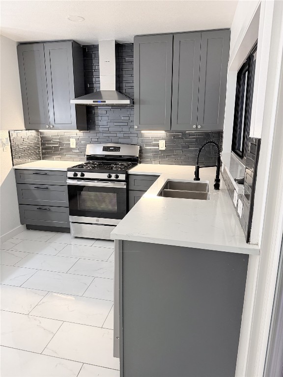 2014 Pecan Street Bastrop, TX 78602 - Photo 4 of 13 Kitchen featuring gray cabinets, wall chimney exhaust hood, stainless steel gas range oven, and light stone counters