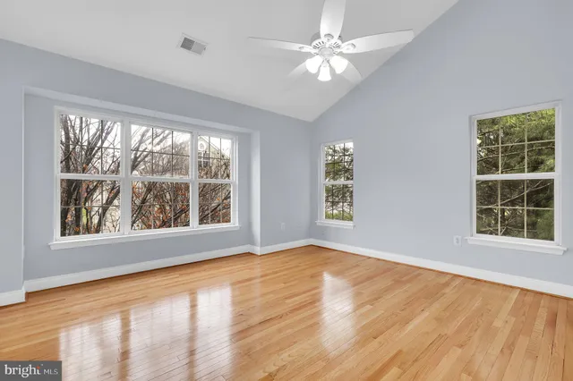 a view of an empty room with a window and wooden floor