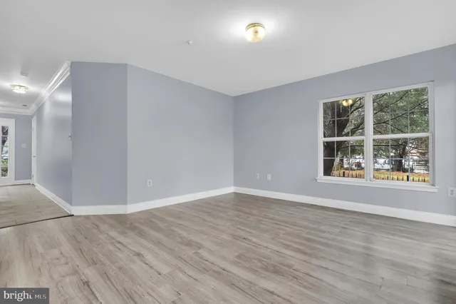 a view of an empty room with wooden floor and windows