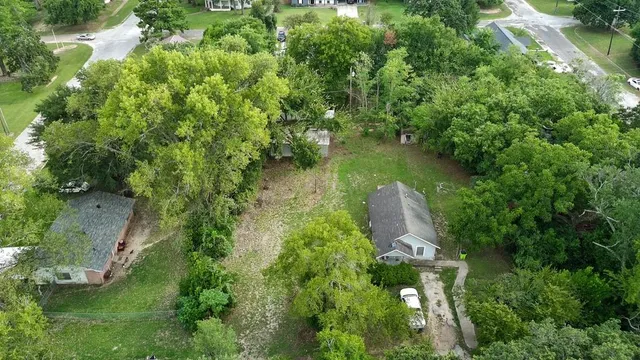 an aerial view of residential houses with outdoor space and trees