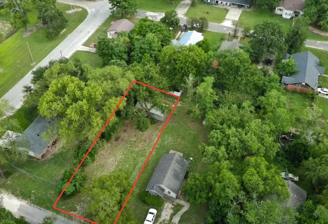 an aerial view of residential houses with outdoor space and trees