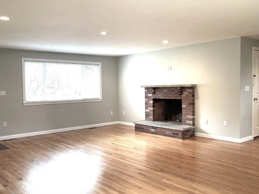 2 McAdams Road Framingham, MA 01701 - Photo 6 of 17 an empty room with wooden floor a fireplace and windows