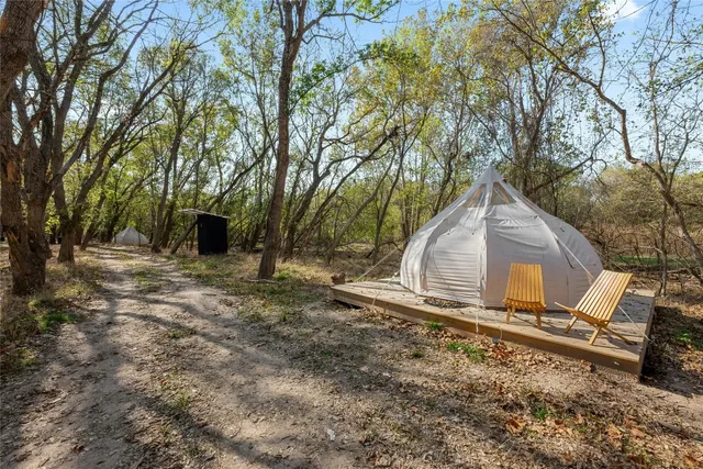 a backyard of a house with large trees and outdoor seating