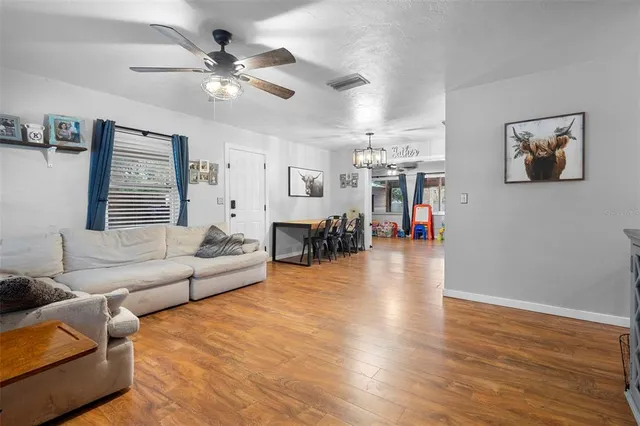 a kitchen with stainless steel appliances kitchen island granite countertop a stove a sink a dining table and chairs with wooden floor