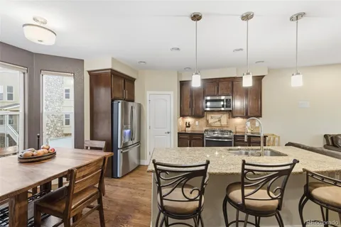 a kitchen with stainless steel appliances kitchen island granite countertop a dining table chairs and refrigerator