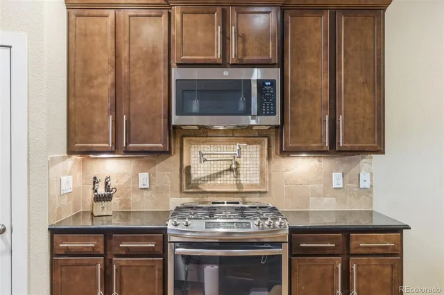a kitchen with granite countertop a stove top oven microwave and cabinets