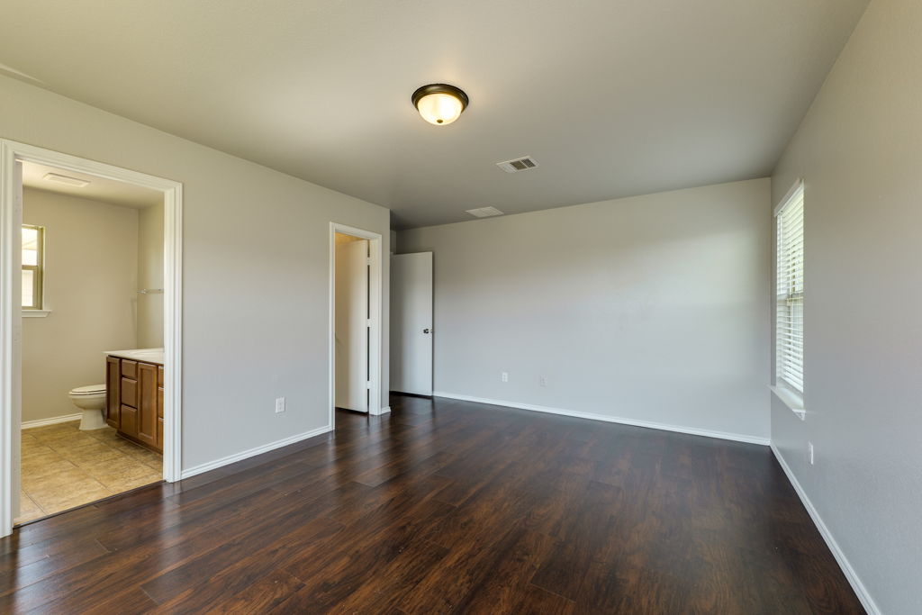 210 Cushman Drive Kyle, TX 78640 - Photo 14 of 21 Spacious room featuring dark wood-finish flooring, light neutral-toned walls, and a recessed window with blinds
