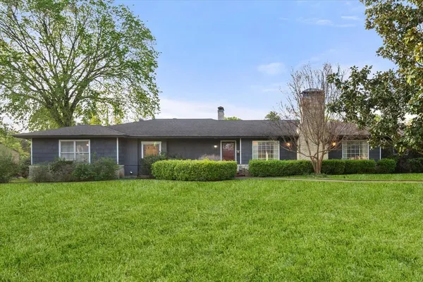 a view of a brick house with a big yard and large trees