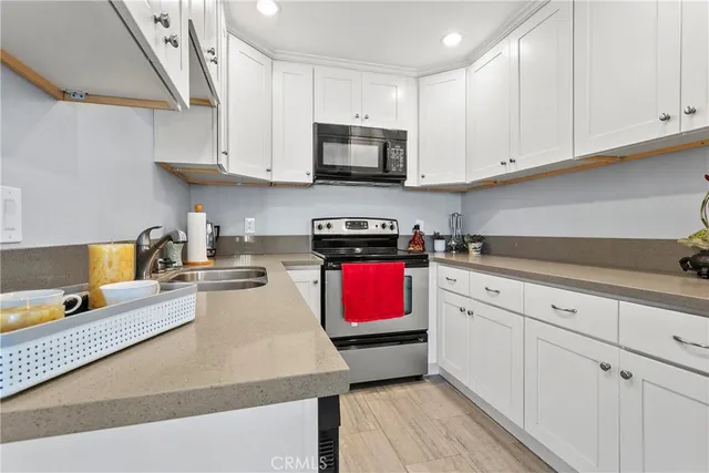 a kitchen with stainless steel appliances granite countertop a stove a sink dishwasher and a microwave with wooden floor