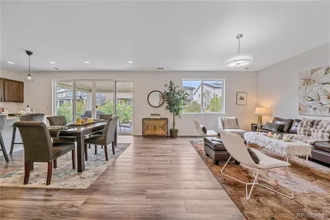 a living room with furniture a dining table with wooden floor and potted plants