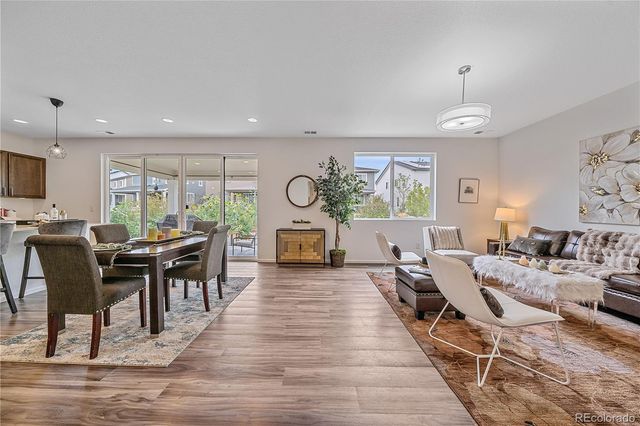 a living room with furniture a dining table with wooden floor and potted plants