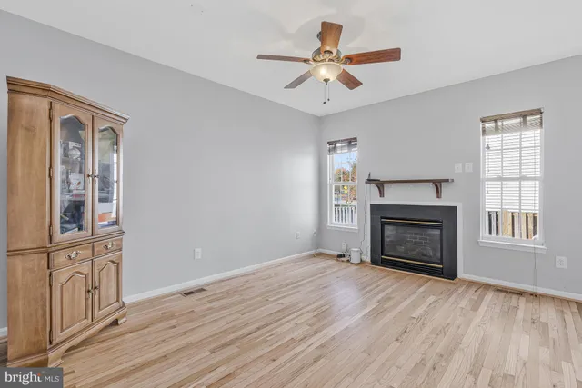 an empty room with windows fireplace and wooden floor