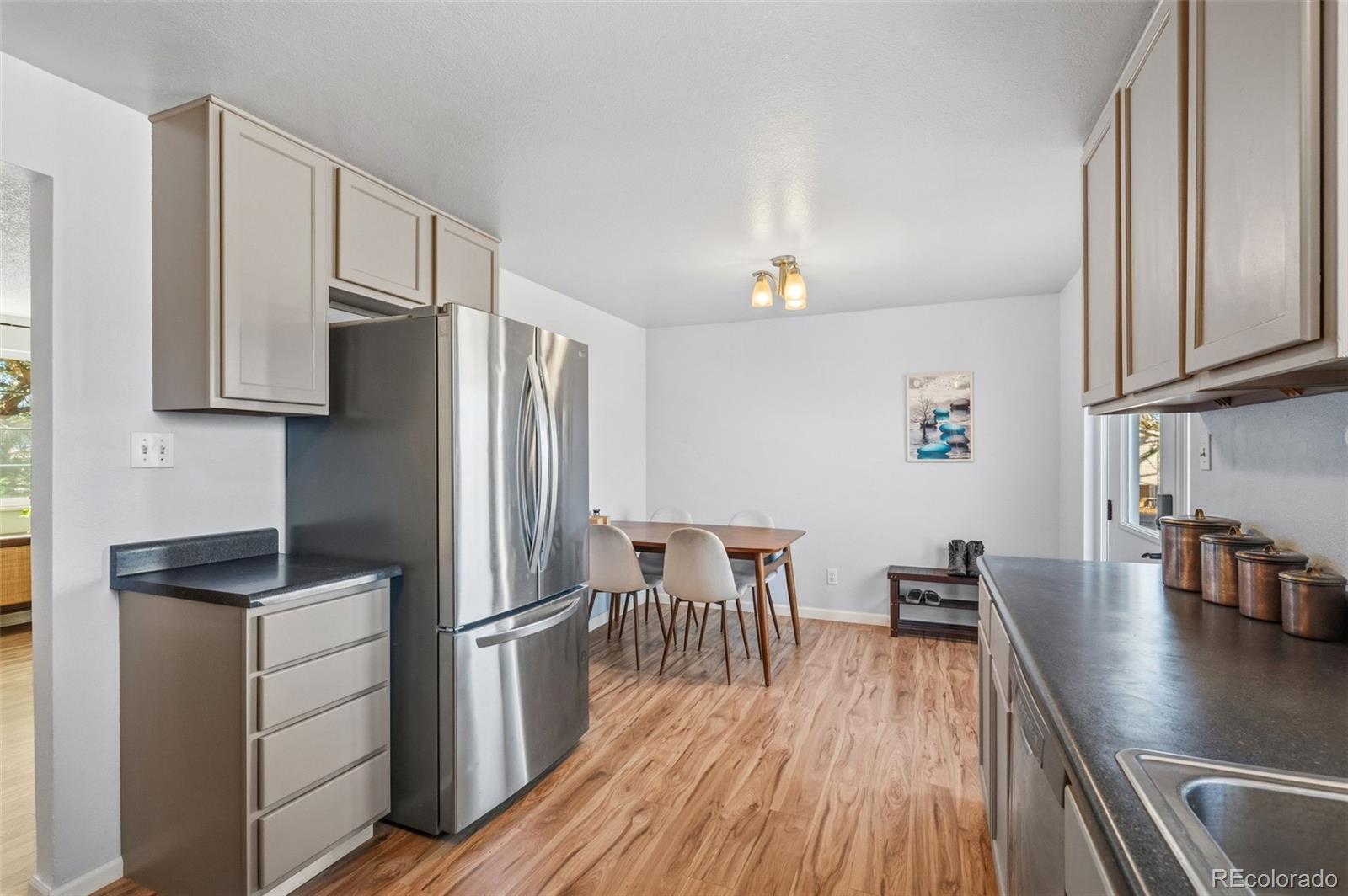 357 Saturn Place Lone Tree, CO 80124 - Photo 4 of 39 a kitchen with stainless steel appliances a refrigerator a stove a dining table and chairs with wooden floor