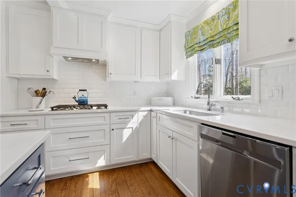 a kitchen with white cabinets and sink