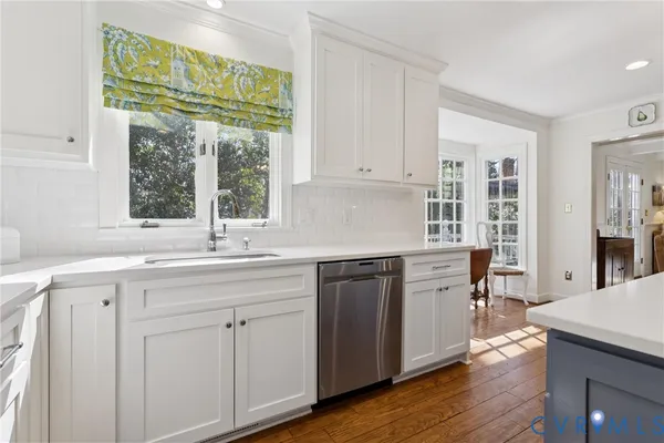 a kitchen with white cabinets and wooden floor