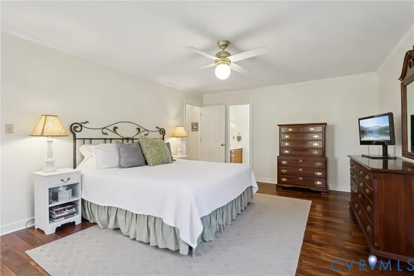 a bedroom with a bed a mirror on dresser and a wooden floor