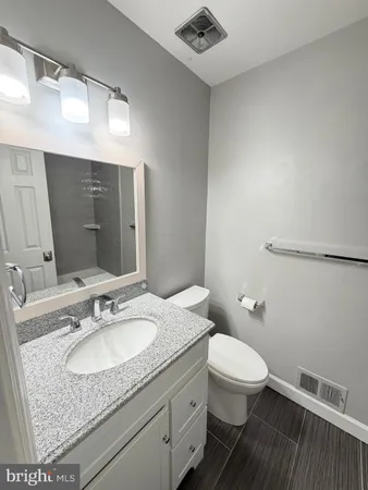 a bathroom with a granite countertop sink a toilet and a mirror