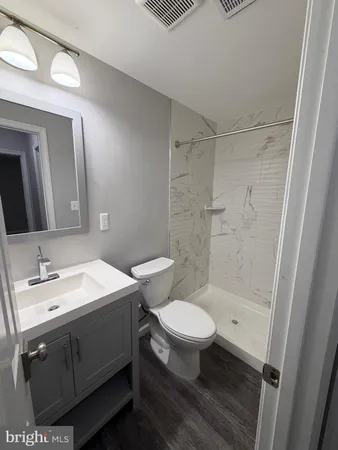 a bathroom with a sink a toilet a mirror and shower
