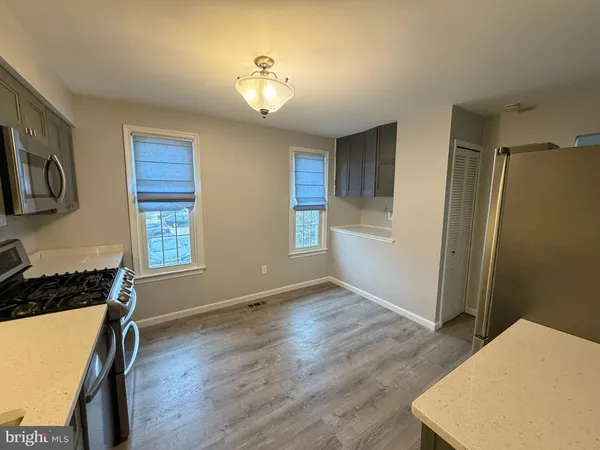 a view of kitchen and empty room with wooden floor