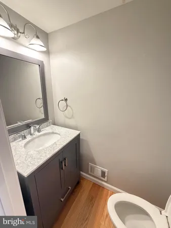 a bathroom with a granite countertop sink vanity mirror and toilet