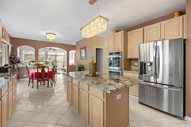 a kitchen with stainless steel appliances granite countertop a refrigerator a oven a kitchen island a stove and a refrigerator