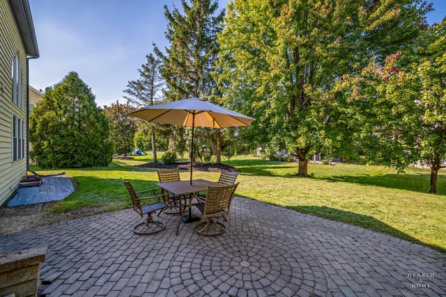 a view of a backyard with table and chairs under an umbrella