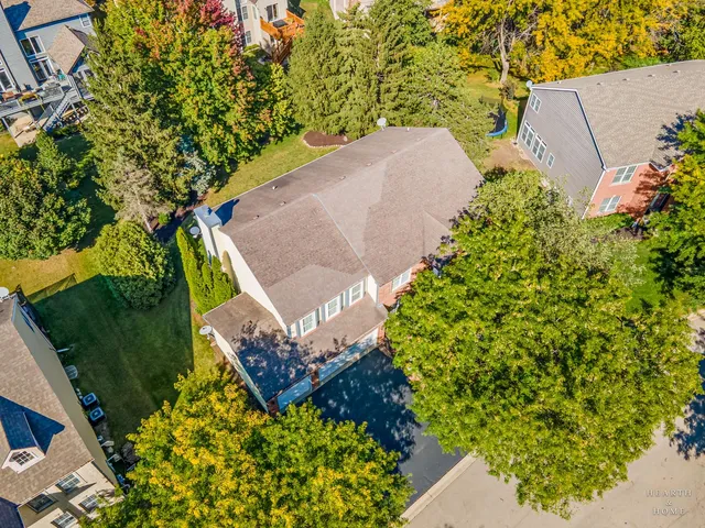 an aerial view of a house with a yard and trees in the back