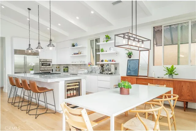 a kitchen with stainless steel appliances granite countertop a stove a sink a dining table and chairs with wooden floor