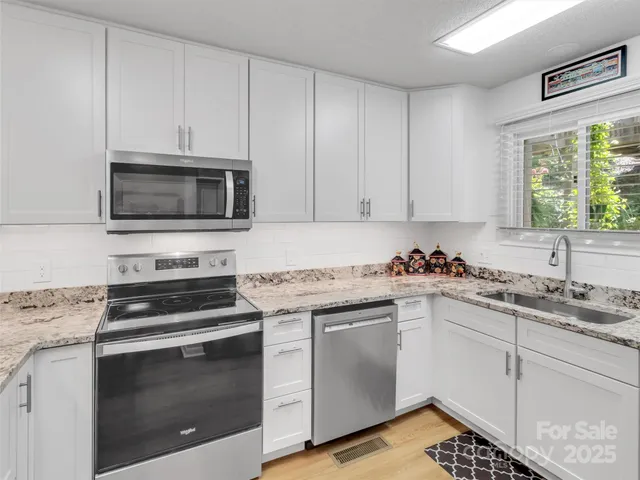 a kitchen with white cabinets appliances and a window