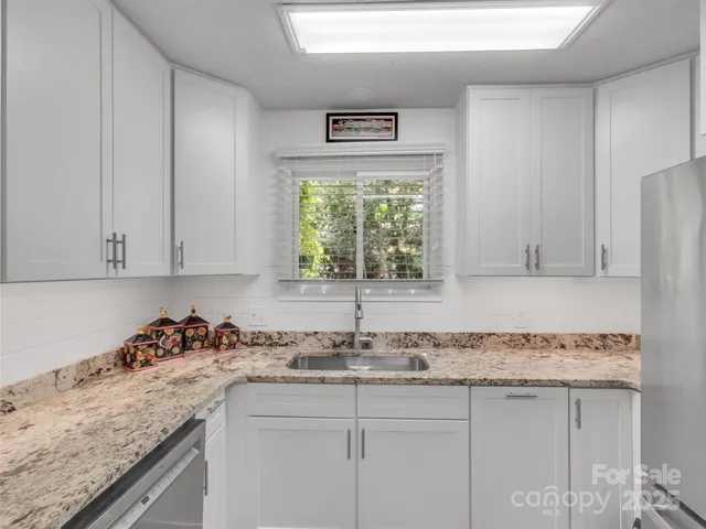 a kitchen with granite countertop a sink window and cabinets