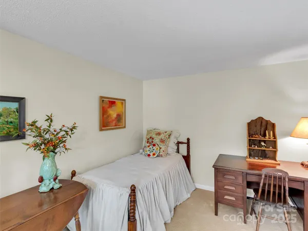 a bedroom with a bed table chair and potted plant