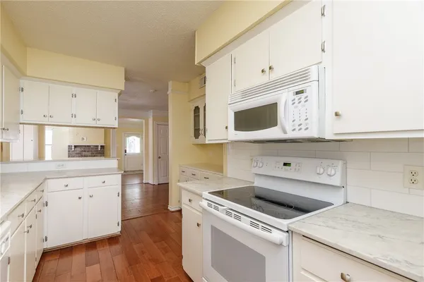 a kitchen with granite countertop white cabinets and white appliances