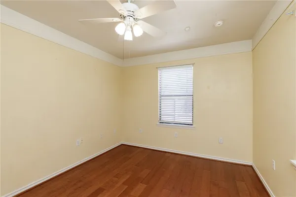 an empty room with wooden floor fan and windows