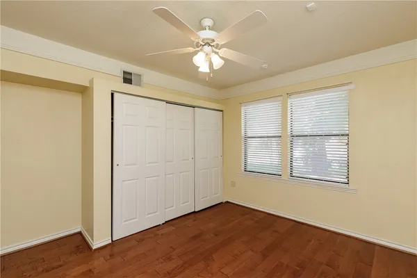 an empty room with wooden floor chandelier fan and windows