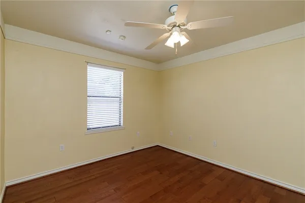 an empty room with wooden floor fan and windows