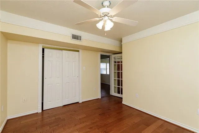 an empty room with a ceiling fan and wooden floor
