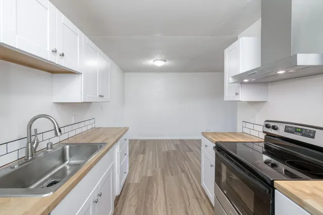 a kitchen with a sink stove top oven and cabinets