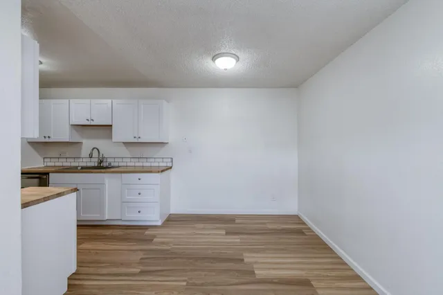 a view of a kitchen with a sink and dishwasher a stove top oven with wooden floor