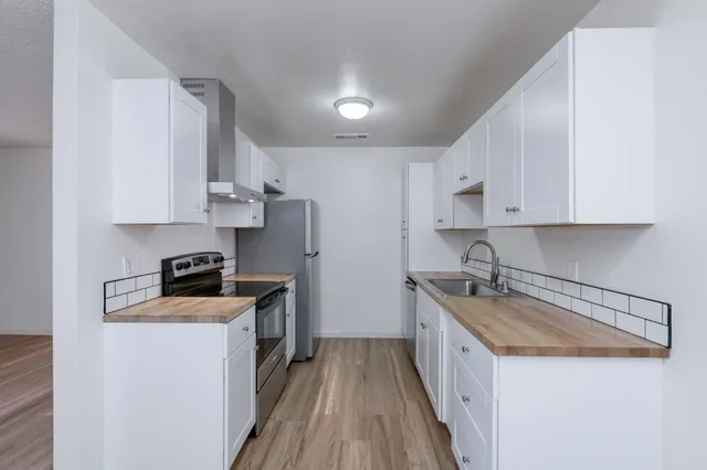 a kitchen with stainless steel appliances a sink stove top oven and white cabinets