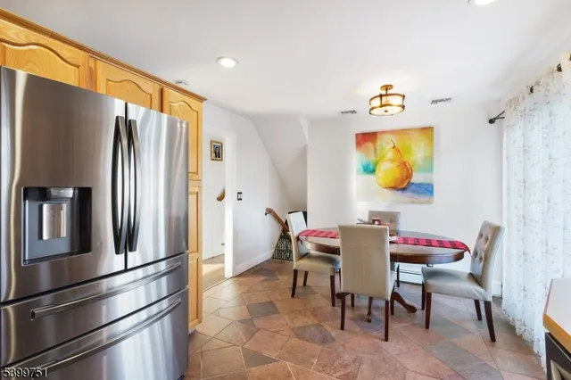 a kitchen with stainless steel appliances granite countertop a refrigerator and a dining table
