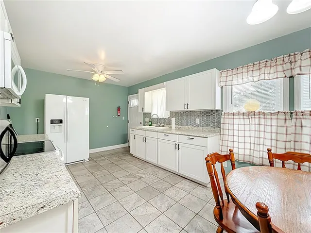 a kitchen with a dining table chairs and white appliances