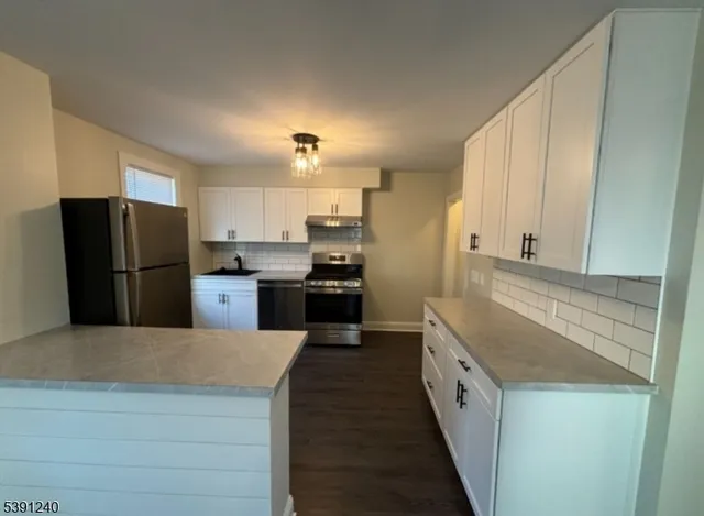 a kitchen with stainless steel appliances granite countertop a refrigerator a stove and a sink